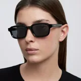 Lentes de sol con montura rectangular de diseño clásico y contemporáneo, con esquinas suavemente redondeadas. Presentan un acabado en color negro tanto en la montura como en los cristales.