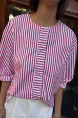 Camisa de lino texturado con diseño a rayas verticales rojas y blancas, cuello babero desmontable en color lila con volados y mangas cortas abullonadas.