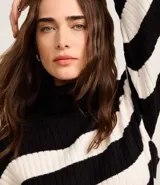 Suéter de punto pesado con cuello alto y mangas largas, presenta un diseño de rayas horizontales en color crema y marrón con textura acanalada.