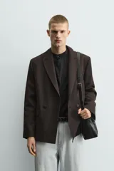 Blazer de corte regular fit confeccionada en tejido con mezcla de lana. Presenta cuello con solapas de pico, cierre frontal de botonadura cruzada, bolsillos con solapa en la cadera y aberturas en la espalda.