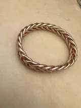 Pulsera de resina flexible con diseño trenzado y acabado brillante, con relleno de lámina metálica en tonos dorados, plateados y cobrizos.