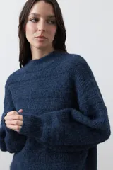 Sweater de punto color marrón chocolate, con cuello redondo, mangas largas abullonadas y puños ajustados. Presenta un diseño de textura acanalada horizontal y silueta relajada.