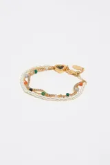 Pulsera dorada multicapa compuesta por una tira de perlas, una cadena fina con pequeños cristales incrustados y cuentas de colores en tonos verdes, naranjas y grises. Presenta un dije en forma de corazón esmaltado en negro y cierre de mosquetón con eslabones de ajuste.