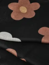 Bufanda negra con estampado de flores en tonos beige y marrón, con centros dorados.
