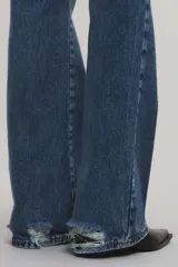 Jeans bootcut de tiro medio color azul, confeccionados en 100% algodón sin elasticidad, con sutiles roturas localizadas y diseño de pernera ensanchada desde la rodilla.