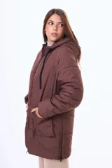 Campera acolchada de corte largo, color negro, con cierre frontal, capucha ajustable con cordones y bolsillos frontales tipo cargo.