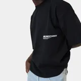 Remera de algodón con corte boxy, color negro, con estampa gráfica en blanco en la parte posterior que incluye el logo de la marca y texto descriptivo.