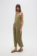 Mono de algodón color verde oliva, con textura plisada, escote en V y tirantes finos tipo lencero. Presenta bolsillos frontales y corte holgado.