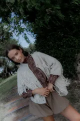 Saco de punto color crudo con diseño de flecos en el frente y mangas, cierre frontal con botones y cuello redondo.