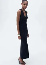 Vestido midi de punto fino color negro, con escote en pico y cuello tipo polo. Diseño sin mangas, entallado al cuerpo.