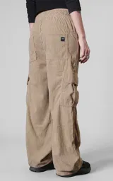 Pantalón cargo de corderoy color arcilla, de calce regular y diseño holgado. Cuenta con seis bolsillos, incluyendo bolsillos laterales tipo cargo con solapa y etiqueta decorativa.