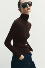 Jersey de punto liso confeccionado en 100% lana, con cuello subido y manga larga. Incluye un cinturón fino integrado a la altura de la cintura.