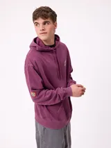 Canguro con capucha de color bordó, con diseño estampado en la espalda en tonos amarillos y blancos, y detalle de parche en la manga. Posee corte holgado y puños elásticos.