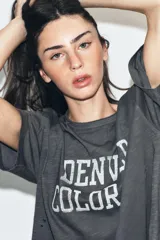 Camiseta de corte oversize confeccionada en algodón flamé, con cuello redondo y manga corta. Presenta un diseño con efecto desgastado, detalles de roturas en el tejido y estampado de texto a contraste en la parte frontal.