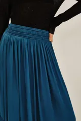 Falda larga de satén en color azul petróleo, con cintura elástica fruncida y un volado amplio en el ruedo.
