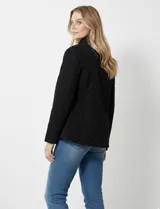 Campera acolchada negra con diseño capitoné de rombos. Posee cuello alto abotonado y cierre frontal oculto con botones a presión dorados. Incluye bolsillos delanteros con solapa y botones a presión dorados.