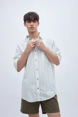 Camisa de manga corta a rayas verticales blancas y verdes, con cuello solapa clásico, bolsillo en el pecho y botones personalizados.