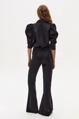 Pantalón de lino negro con corte acampanado, tiro medio-alto, pretina ancha, cierre frontal oculto y bolsillos laterales.