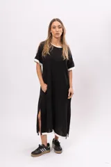 Vestido remerón largo de manga corta color negro, con cuello y puños blancos, y aberturas laterales.