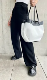 Pantalón negro de lino, de corte ancho y largo, con diseño suelto y botones decorativos en la cintura.