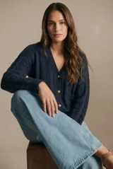 Cardigan de punto texturado con diseño de ochos, color azul marino, con escote en V, cierre frontal con botones dorados y mangas largas con puños acanalados.