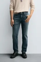 Pantalón de jean corte slim fit, color gris con efecto lavado. Presenta diseño de cinco bolsillos, cierre frontal con cremallera y botón, y tejido elástico.