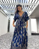 Vestido túnica largo azul con estampado de arabescos dorados, escote en V y mangas cortas.