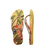 Sandalias Havaianas Slim Tropical, con base estampada con motivos florales en tonos amarillos, naranjas y verdes, y tiras finas color bronce.