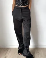 Pantalón sastrero de satén negro, de corte recto y tiro medio. Presenta bolsillos laterales y un detalle de lazo ajustable en los tobillos.