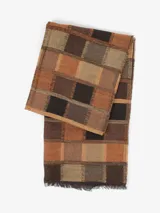 Bufanda de estilo clásico y versátil, con patrón de cuadros en tonos marrones, naranjas, beige y negro. Presenta flecos en los extremos.