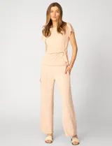 Remera de manga corta color beige, confeccionada en mezcla de modal, con cuello redondo y detalle de lazo lateral que genera un drapeado natural en la cintura.