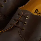 Zapatos de cuero Dr. Martens modelo 1461, con acabado desgastado, cordones y suela de goma con costuras amarillas visibles.