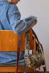 Bandolera de cuero color rojo con detalles en negro, con correa regulable y cierre superior con cremallera.