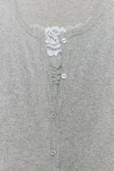 Chaqueta de punto color beige con escote en pico y manga larga, que incluye un top interior integrado con detalle de encaje a tono. Cierre frontal mediante botones.