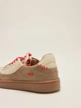 Championes urbanos de cuero en tonos tostado y marrón claro, con detalles en rojo, cordones bicolor, suela de goma y el número 1986 bordado en el talón.