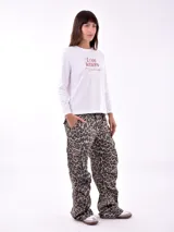 Remera de manga larga color crema con cuello redondo y un estampado central de un ramo de flores rosadas y naranjas en un jarrón azul oscuro.