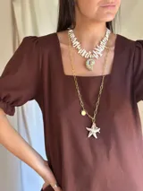 Collar corto con cuentas irregulares de nácar color blanco y dije de caracol con detalles dorados. Cierre con gancho y cadena de acero quirúrgico para regular el largo.