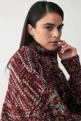 Sweater de punto grueso con cuello alto, confeccionado en una mezcla de hilos de colores que crean un efecto jaspeado en tonos bordó, naranja, amarillo y celeste.