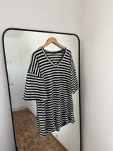 Vestido corto negro con rayas horizontales blancas, escote en V y mangas cortas acampanadas.