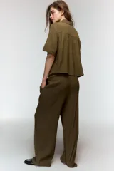 Camisa de cuello solapa y escote en pico, con mangas cortas que incluyen trabilla y botón. Presenta un cierre frontal con botones y un diseño de corte recto.