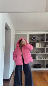 Campera puffer de corte holgado en color beige, con diseño acolchado, cuello alto y capucha desmontable. Cuenta con cierre frontal y botones a presión, además de puños elásticos.