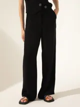 Pantalón negro de crepe con cintura cruzada, broche con brillo glitter, tiro alto, pinzado y pata ancha.