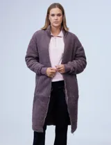 Campera larga de sherpa color violeta, con cierre frontal completo, cuello alto y puños de tejido elástico. Cuenta con bolsillos laterales.