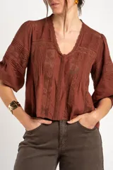 Blusa de viscosa y lino color crudo, con cuello en V, mangas tres cuartos abullonadas e inserciones de encaje floral y detalles plisados frontales.