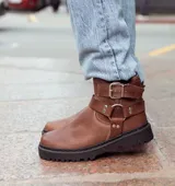 Botas de caña baja color chocolate, realizadas en cuero encerado, con hebillas en la caña y herrajes de níquel. El fondo es de suela negra realizado artesanalmente y el interior está forrado en forrería vacuna.