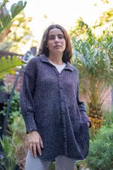 Camisa tejida en punto calado con hilo de algodón y lurex, de silueta oversize. Presenta mangas 3/4 ligeramente abullonadas, cuello camisero clásico y cierre frontal con botones metálicos.