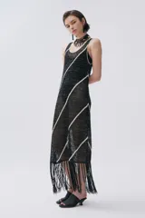 Vestido largo de punto calado negro con lurex y rayas diagonales blancas. Tiene escote redondo y flecos en el ruedo.