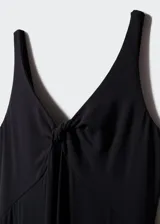 Vestido largo de punto fluido color negro, con escote en V y detalle de nudo en el pecho. Presenta tirantes anchos y diseño evasé con espalda escotada.