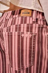 Short de tiro alto confeccionado en denim con diseño a rayas en tonos rosados, borravino y blancas. Cuenta con bolsillos delanteros y traseros, presillas para cinto y cierre frontal con botón metálico y cremallera.