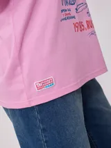 Remera oversize blanca de algodón con estampa frontal temática de surf camp en tonos azules y salmón.